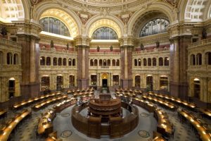 photo of the main reading room at the Library of Congress, an open circular room with reading desks and bookcases in connecting rooms