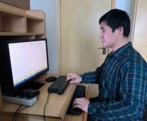 photo of a man using a computer with a braille display