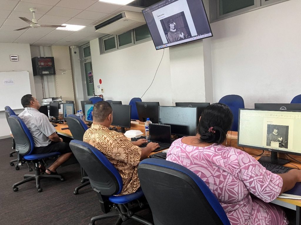 three trainees are pictured sitting in a computer room working on course materials